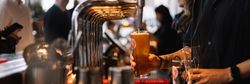 Bartender pouring a glass of beer from a tap at a busy bar