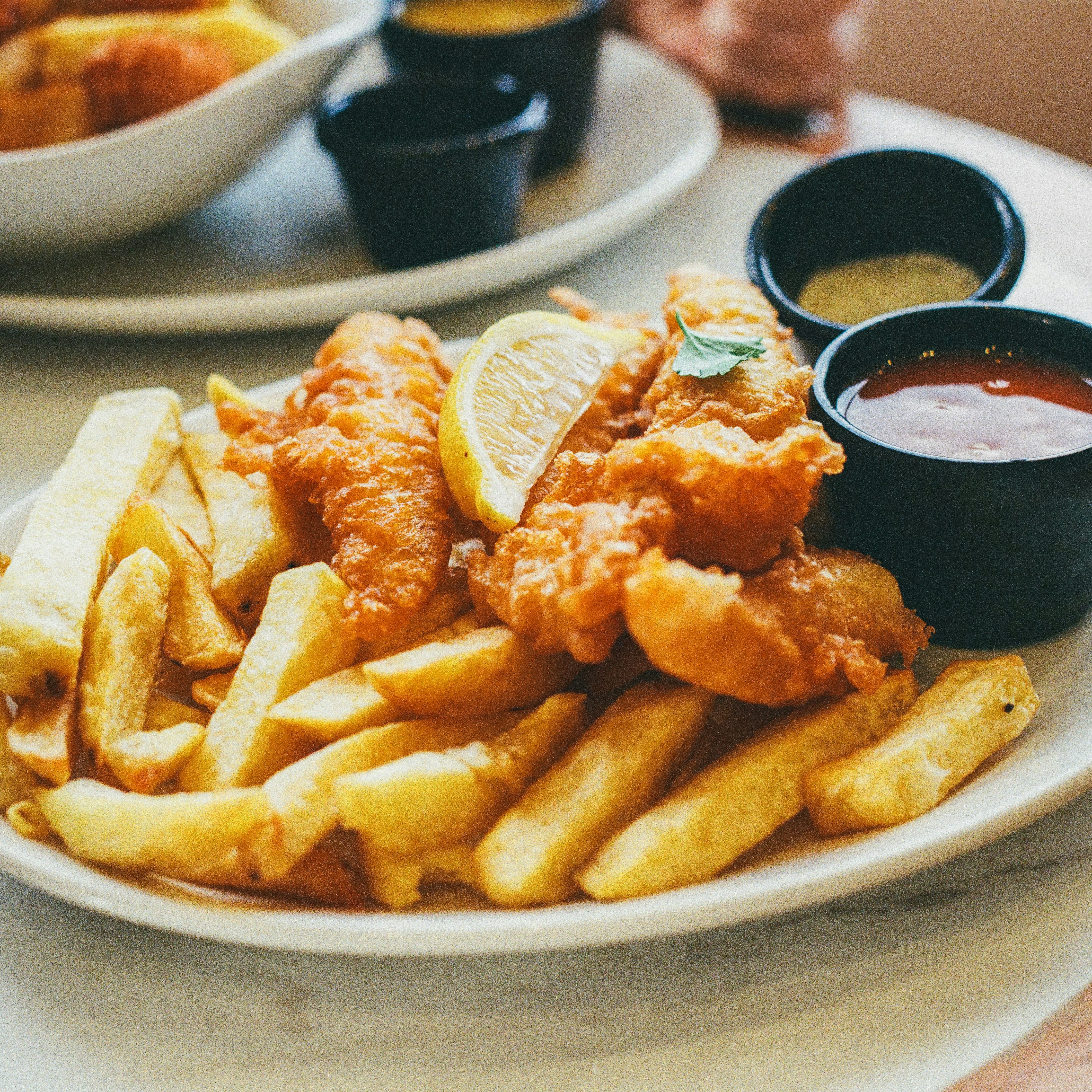 Plate of fish and chips with dipping sauces and a lemon wedge