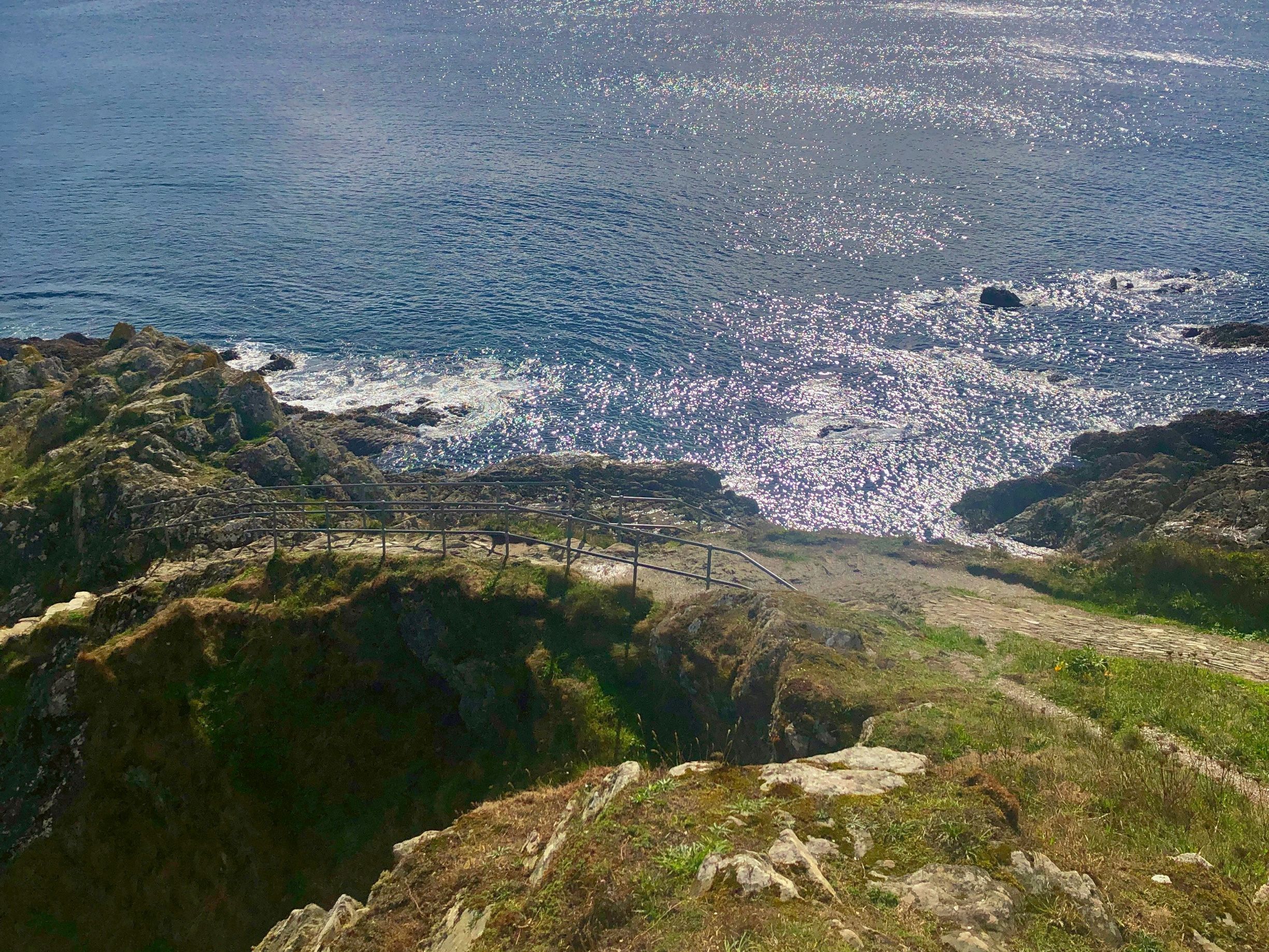 Rocky coastline with shimmering ocean and dramatic cloudy sky