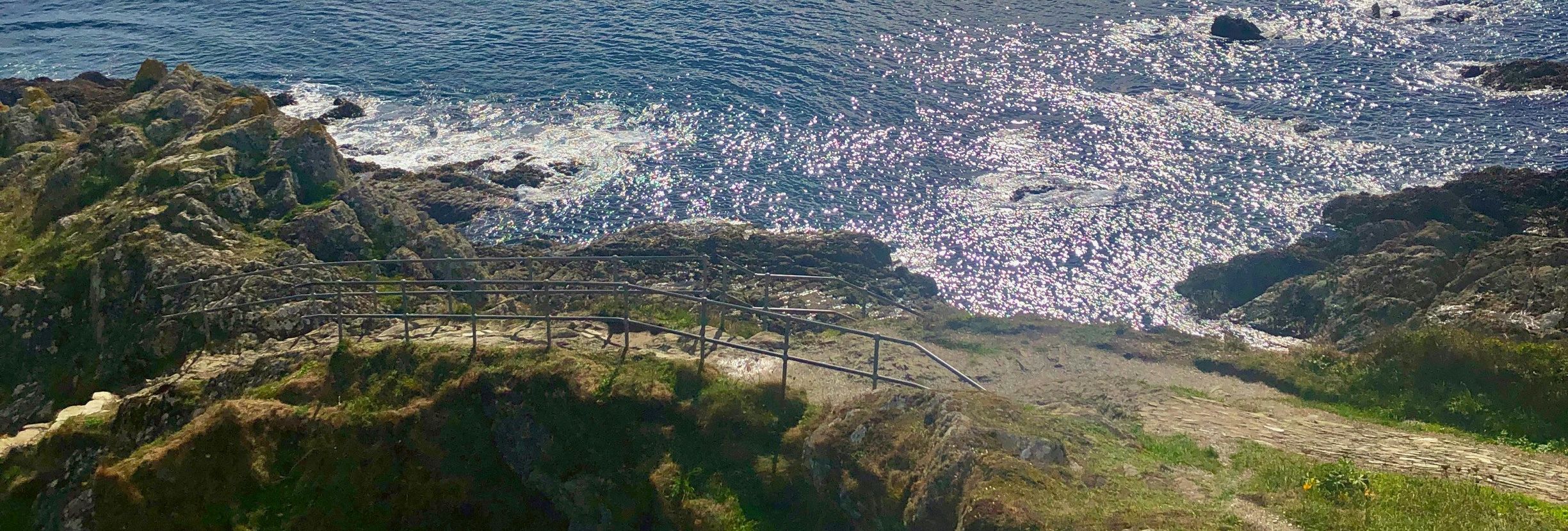 Rocky coastline with shimmering ocean and dramatic cloudy sky
