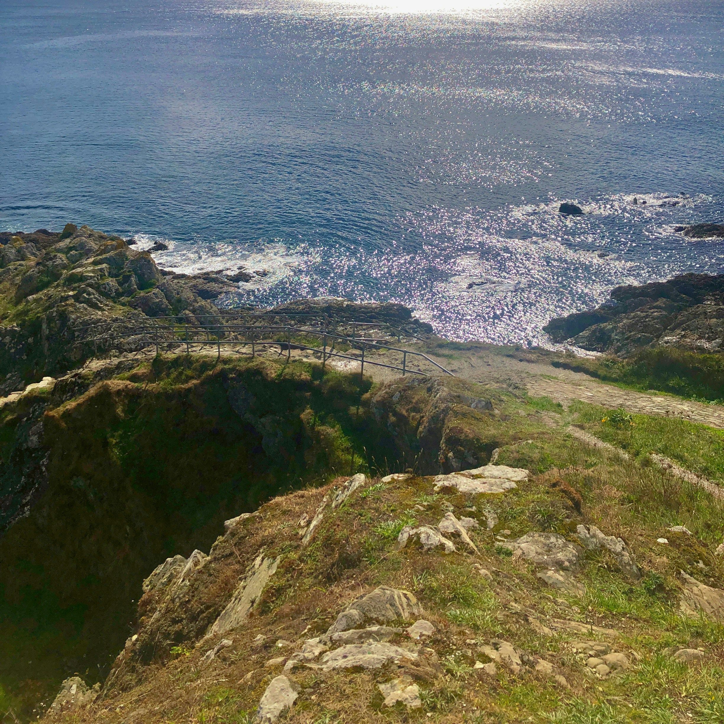 Rocky coastline with shimmering ocean and dramatic cloudy sky