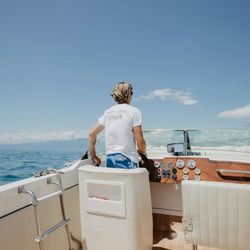 Person steering a boat on a sunny day with ocean and blue sky