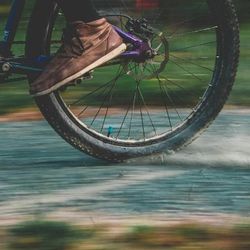 Close-up of a person riding a bicycle at high speed on a paved path