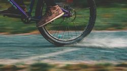 Close-up of a person riding a bicycle at high speed on a paved path