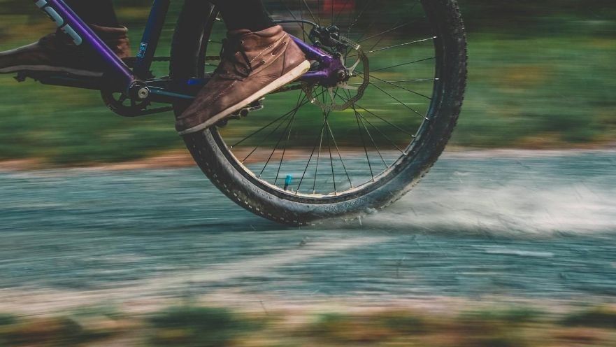 Close-up of a person riding a bicycle at high speed on a paved path