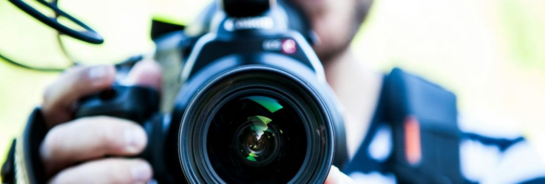 Person holding a DSLR camera close to the lens
