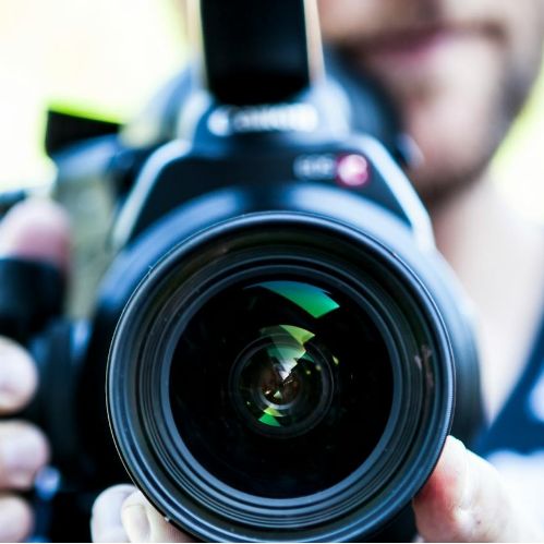 Person holding a DSLR camera close to the lens