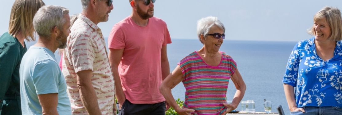 Group of people standing outdoors with the sea in the background