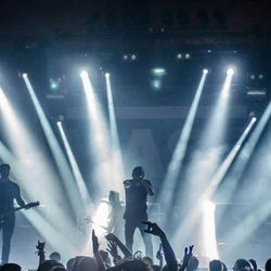 Rock band performing on stage with dramatic lighting and an enthusiastic audience