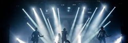 Rock band performing on stage with dramatic lighting and an enthusiastic audience
