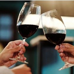 Two people clinking glasses of red wine
