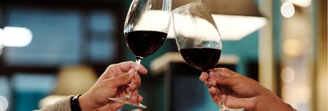 Two people clinking glasses of red wine