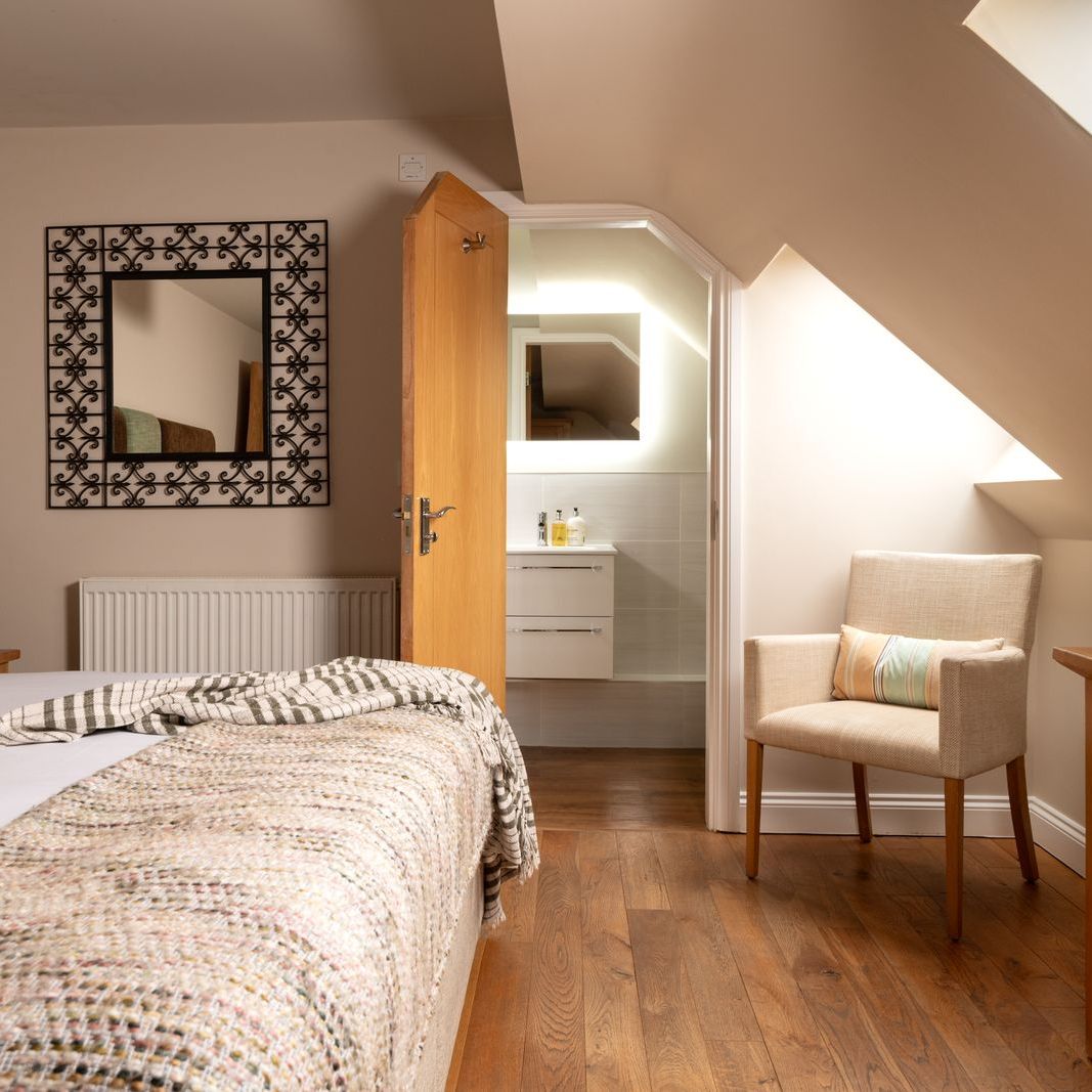 Cozy attic bedroom with double bed, wooden furniture, and en-suite bathroom.