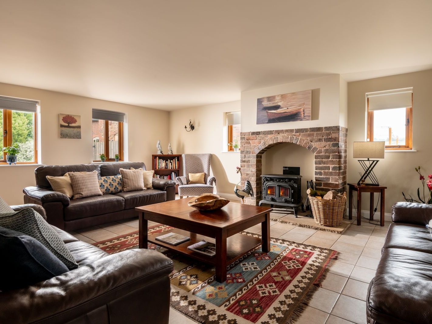 Cozy living room with leather sofas, wood burner, and patterned rug