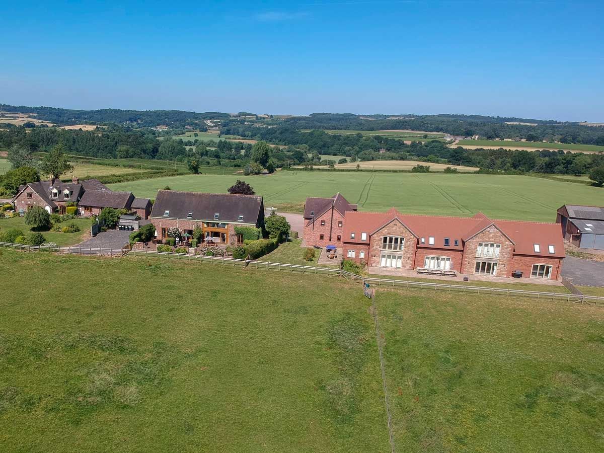 Aerial view of a rural property with multiple large brick houses surrounded by fields and countryside.