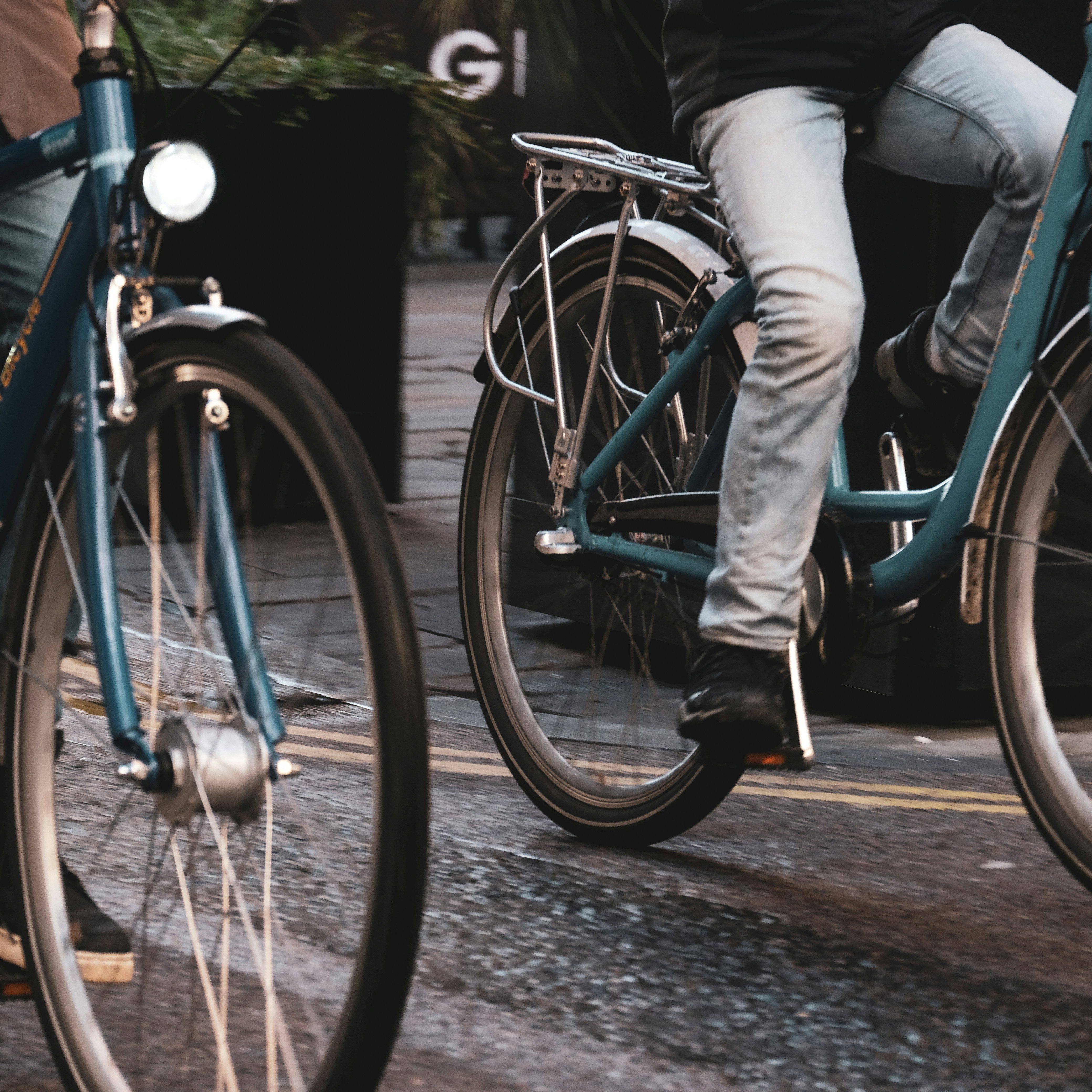 Two people riding blue bicycles on a city street