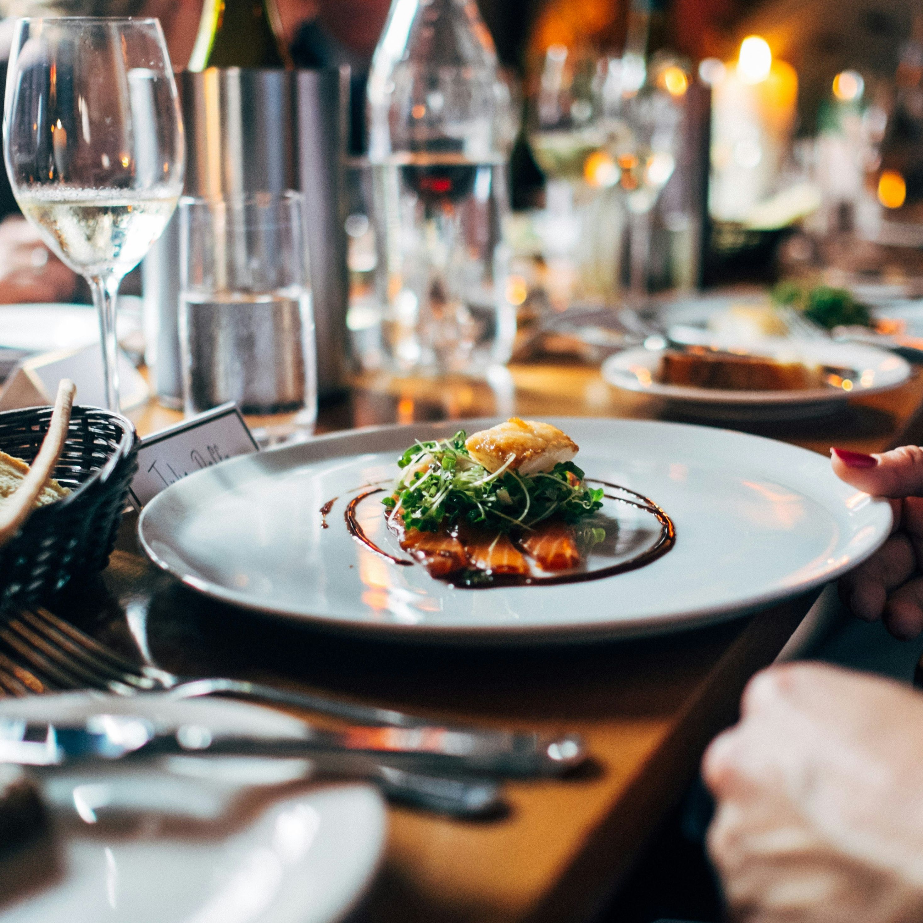 Elegant dinner setting with gourmet dish, wine glasses, and bread basket
