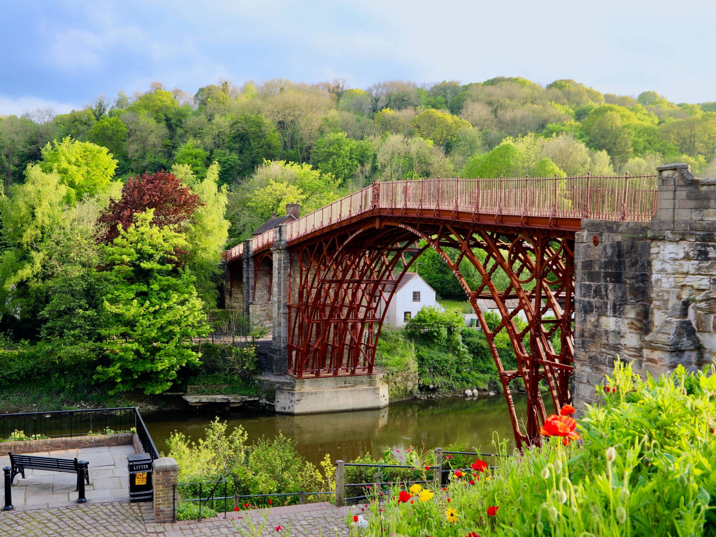 The Iron Bridge spanning across a river surrounded by lush green trees and flowers.