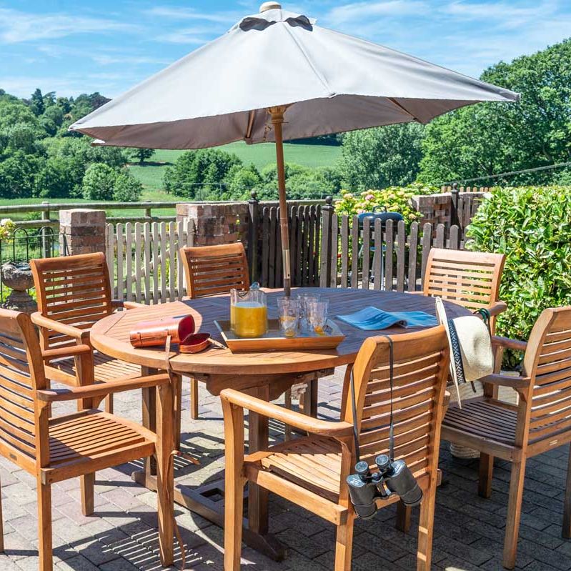 Patio table and chairs with sun umbrella in a garden setting