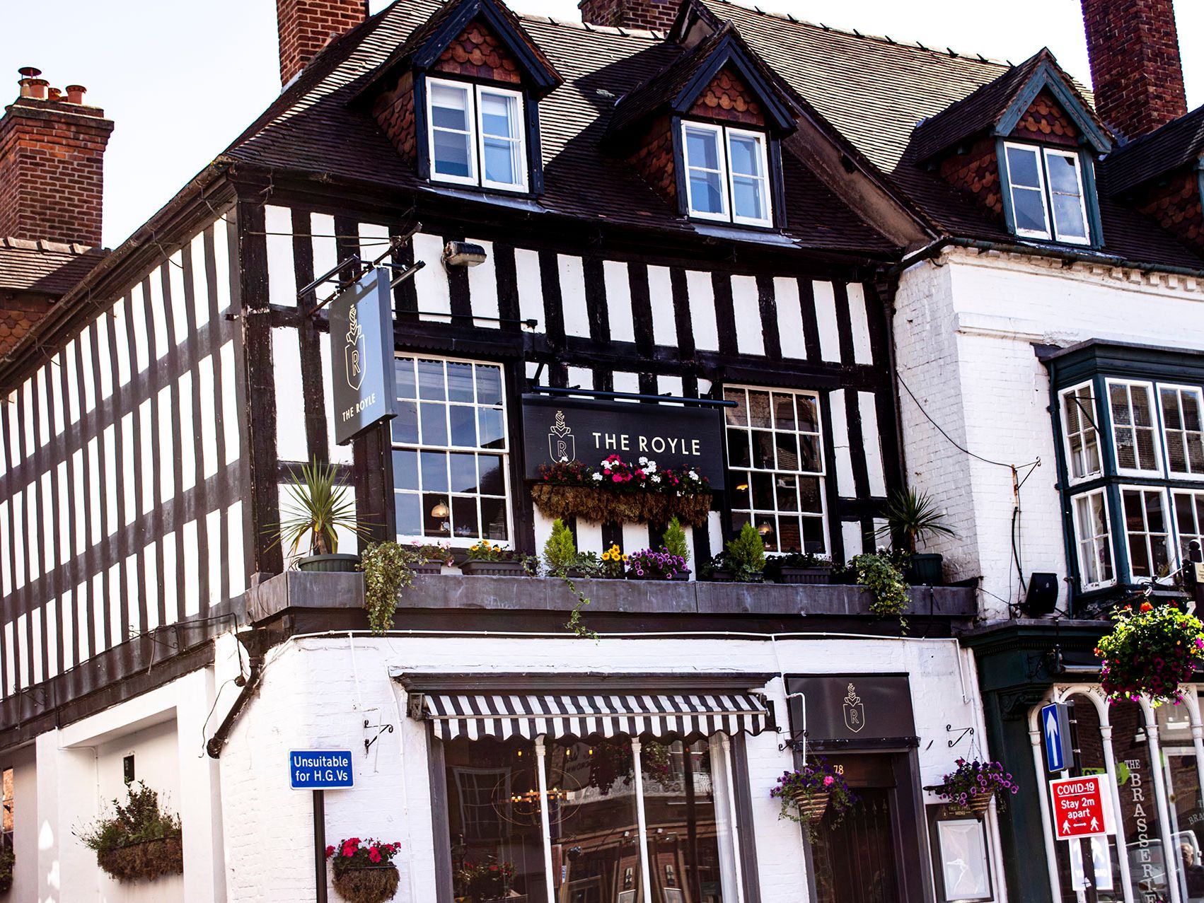 Black and white timber-framed building with a sign reading 'The Royle' and flower boxes under the windows.