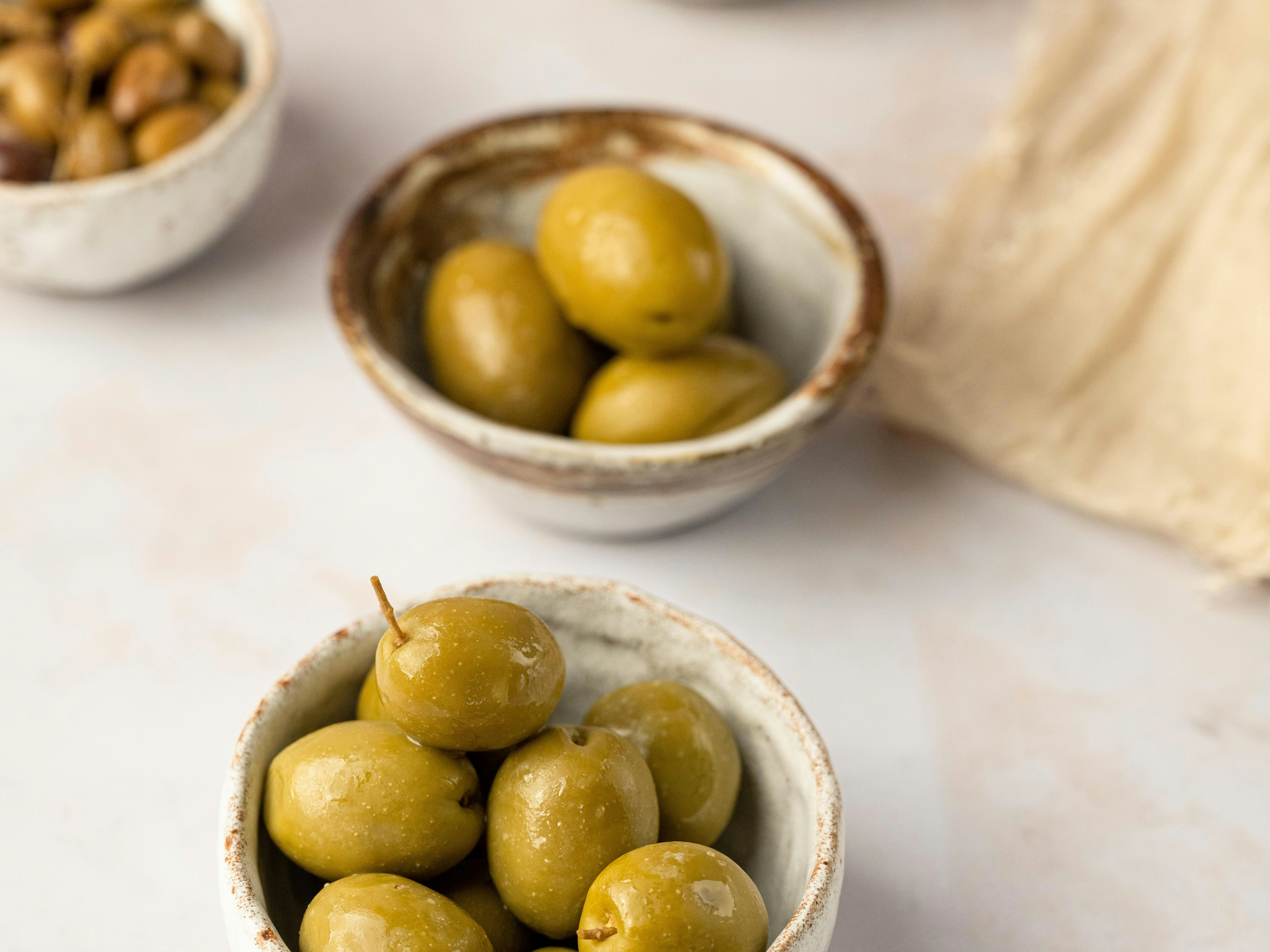 Assorted bowls of olives on a light surface