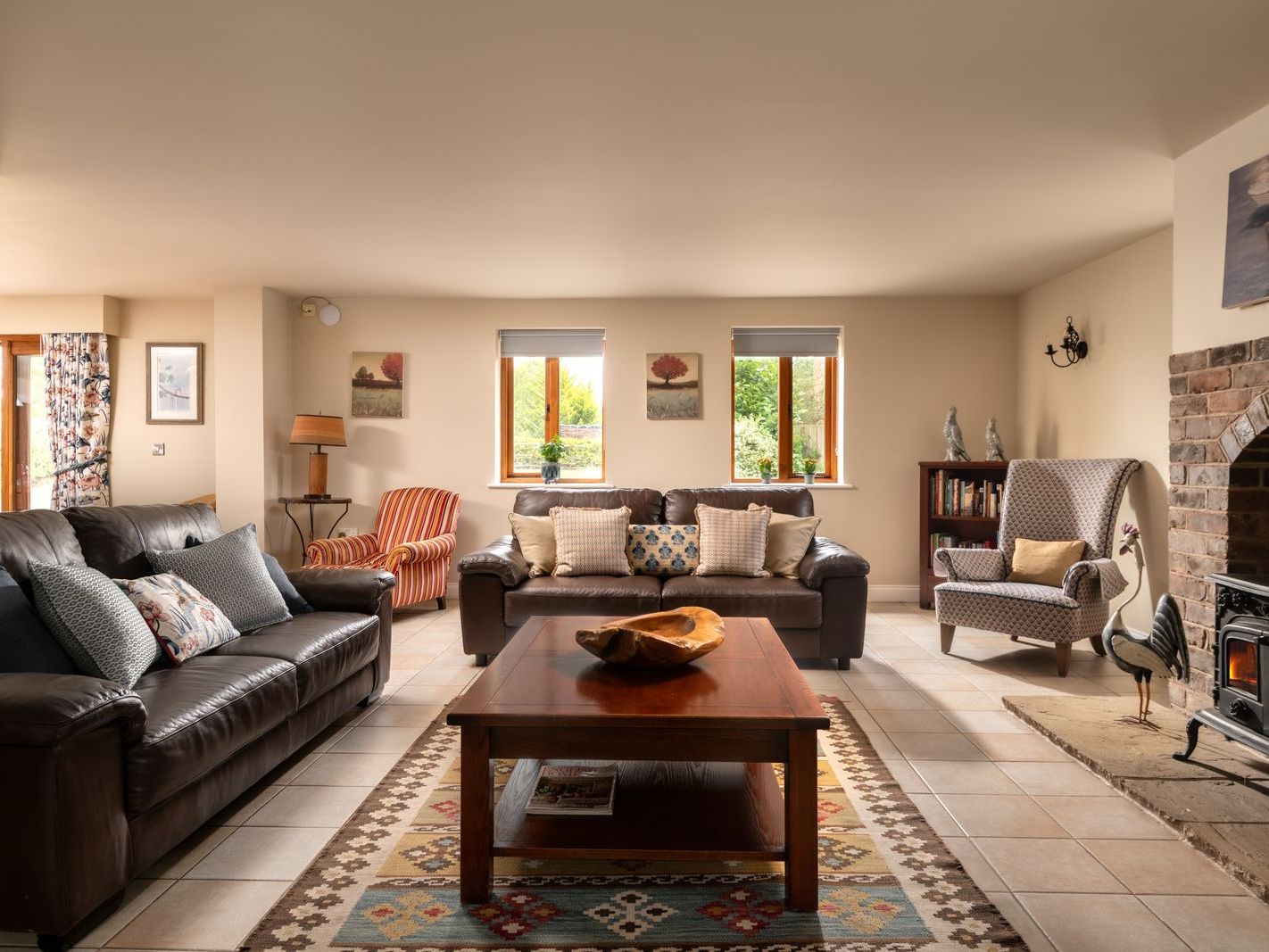 Cozy living room with leather sofas, armchairs, wooden coffee table, and fireplace