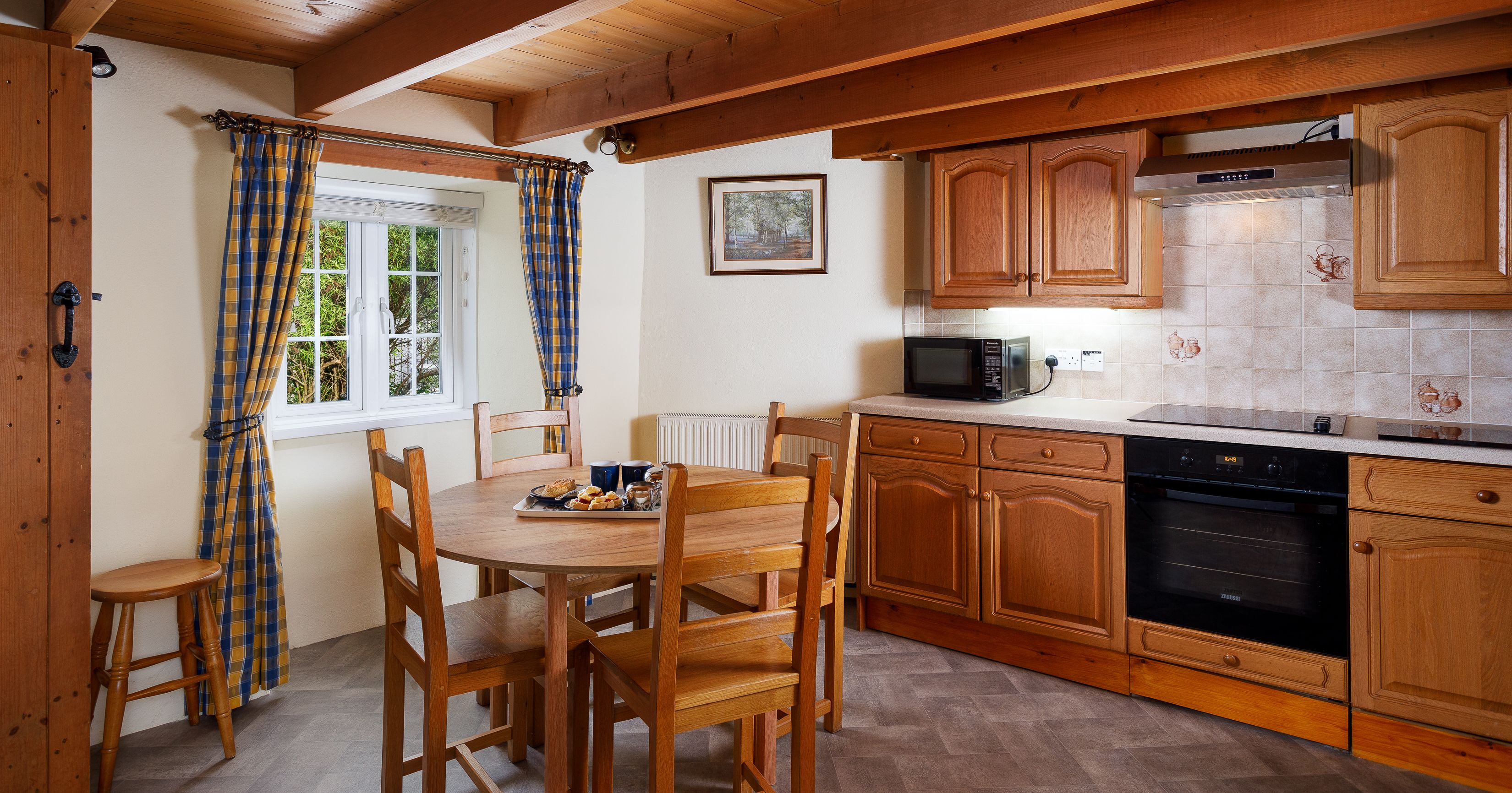 Cozy kitchen with wooden cabinets, dining table, and checkered curtains