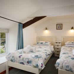 Twin bedroom with two single beds, floral bedding, and a window with a countryside view.