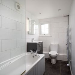 Modern bathroom with bathtub, toilet, sink and grey vanity unit