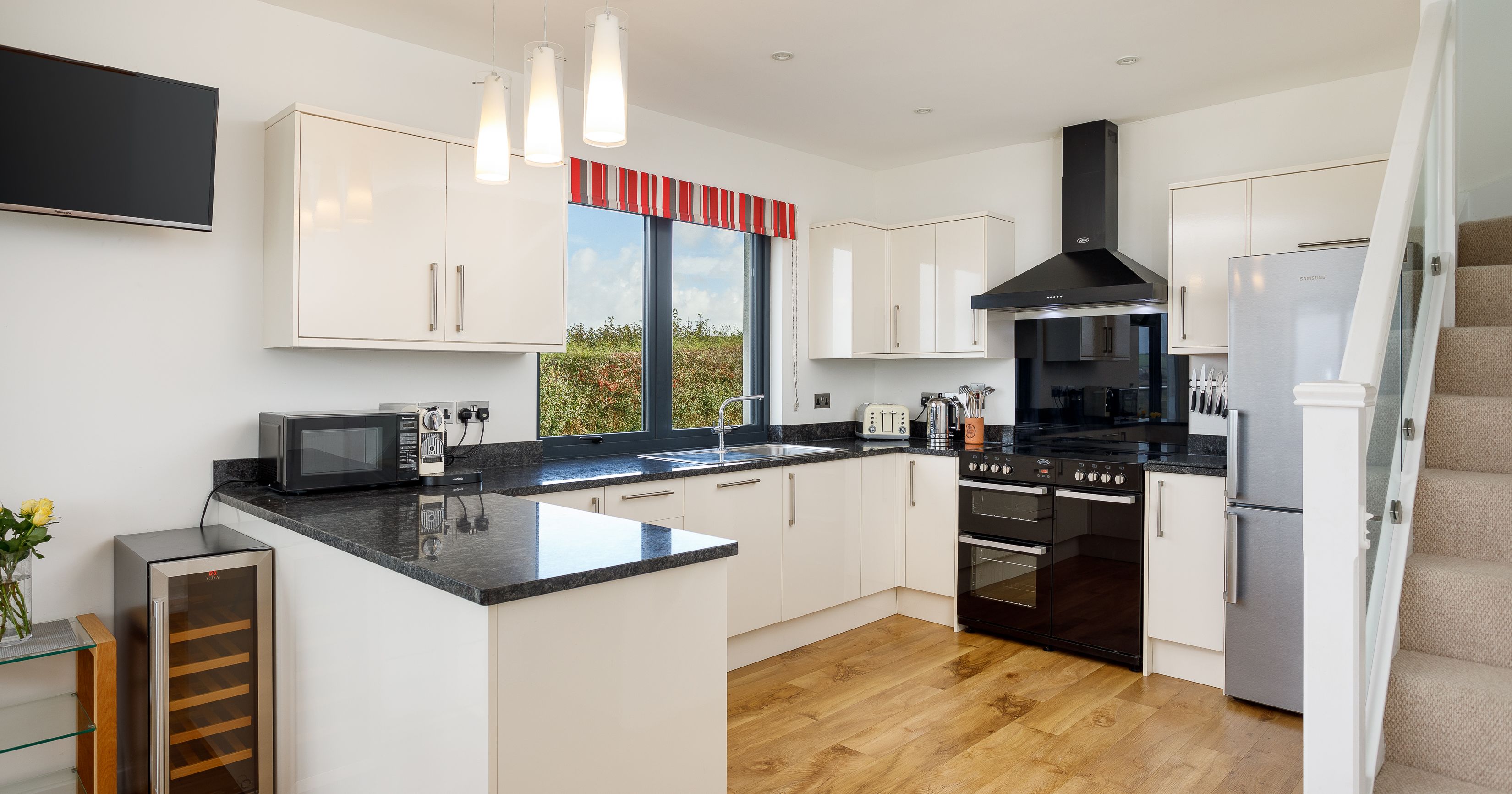 Modern kitchen with white cabinets, black countertops, and stainless steel appliances.