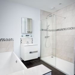 Modern bathroom with a bathtub, walk-in shower, vanity unit and light tiles