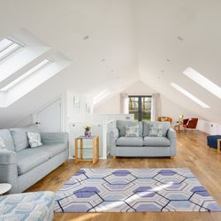 Bright and spacious loft living room with modern furniture, wooden floors, skylights, and cozy seating area.
