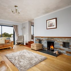 Cozy living room with leather sofas, stone fireplace, and large window with countryside view