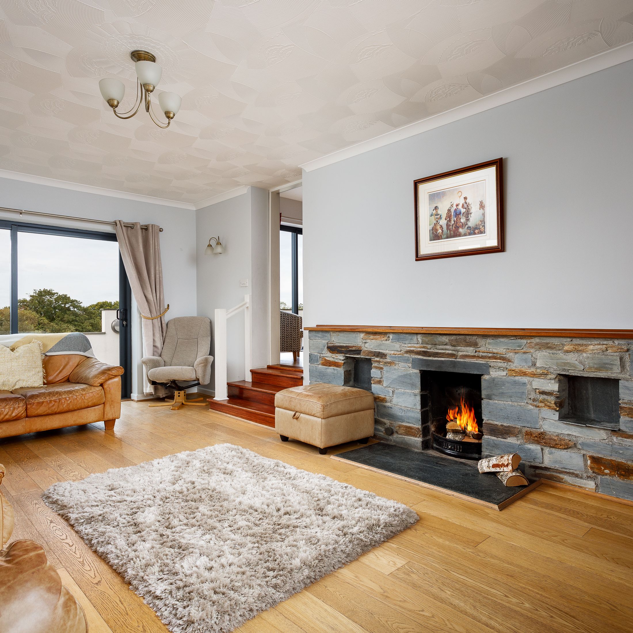 Cozy living room with leather sofas, stone fireplace, and large window with countryside view