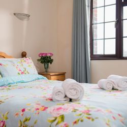 Bedroom with floral bedding and rolled towels on the bed