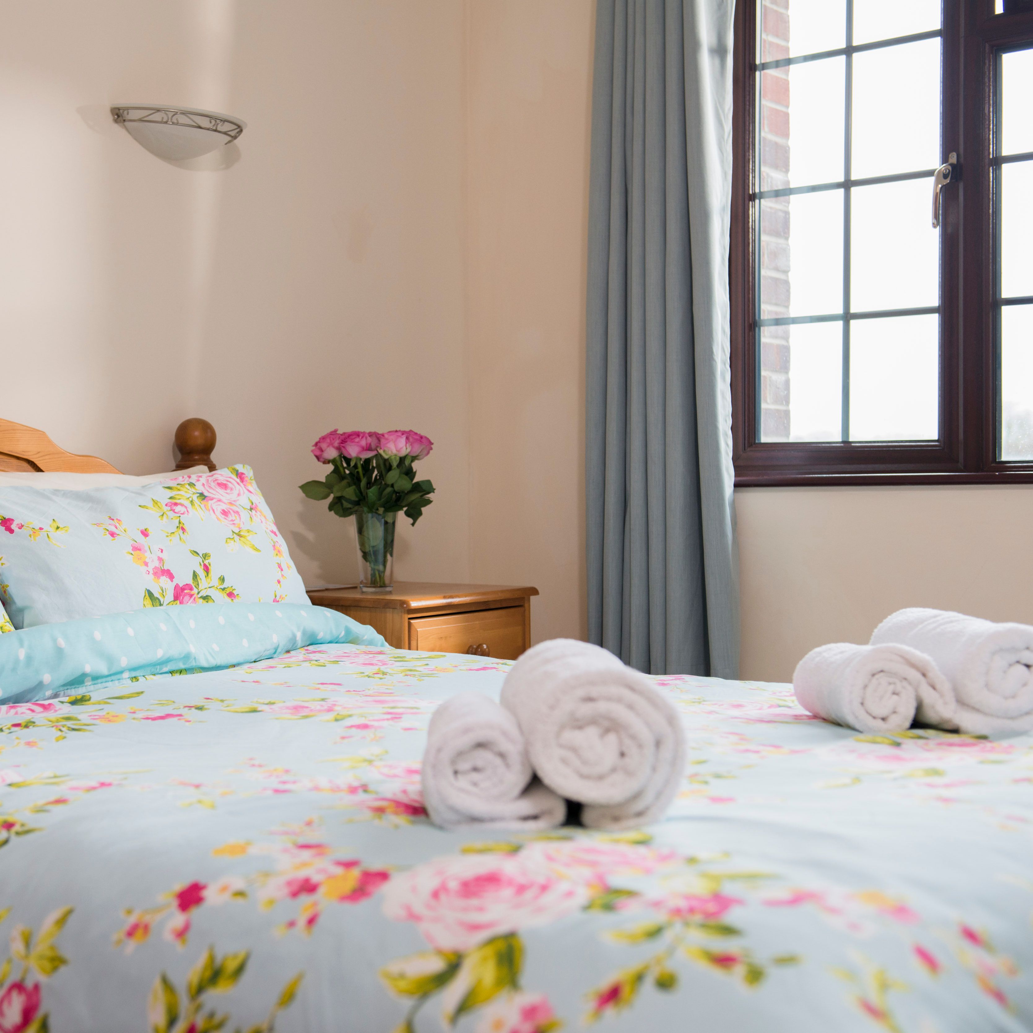 Bedroom with floral bedding and rolled towels on the bed