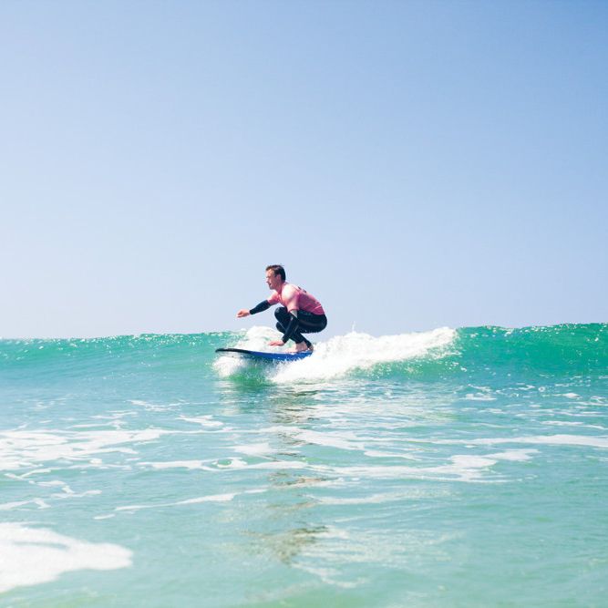 Person surfing on a wave under a clear blue sky