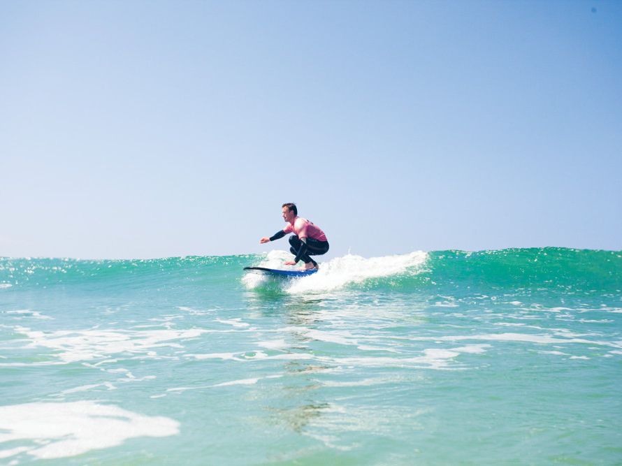 Person surfing on a wave under a clear blue sky