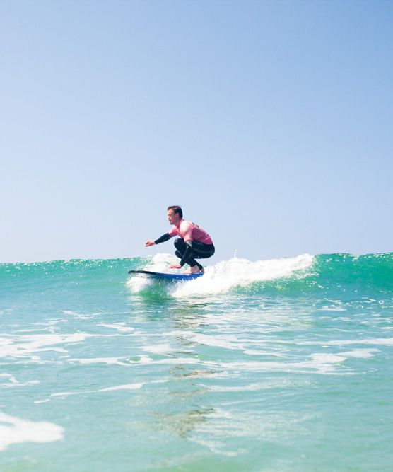 Person surfing on a wave under a clear blue sky