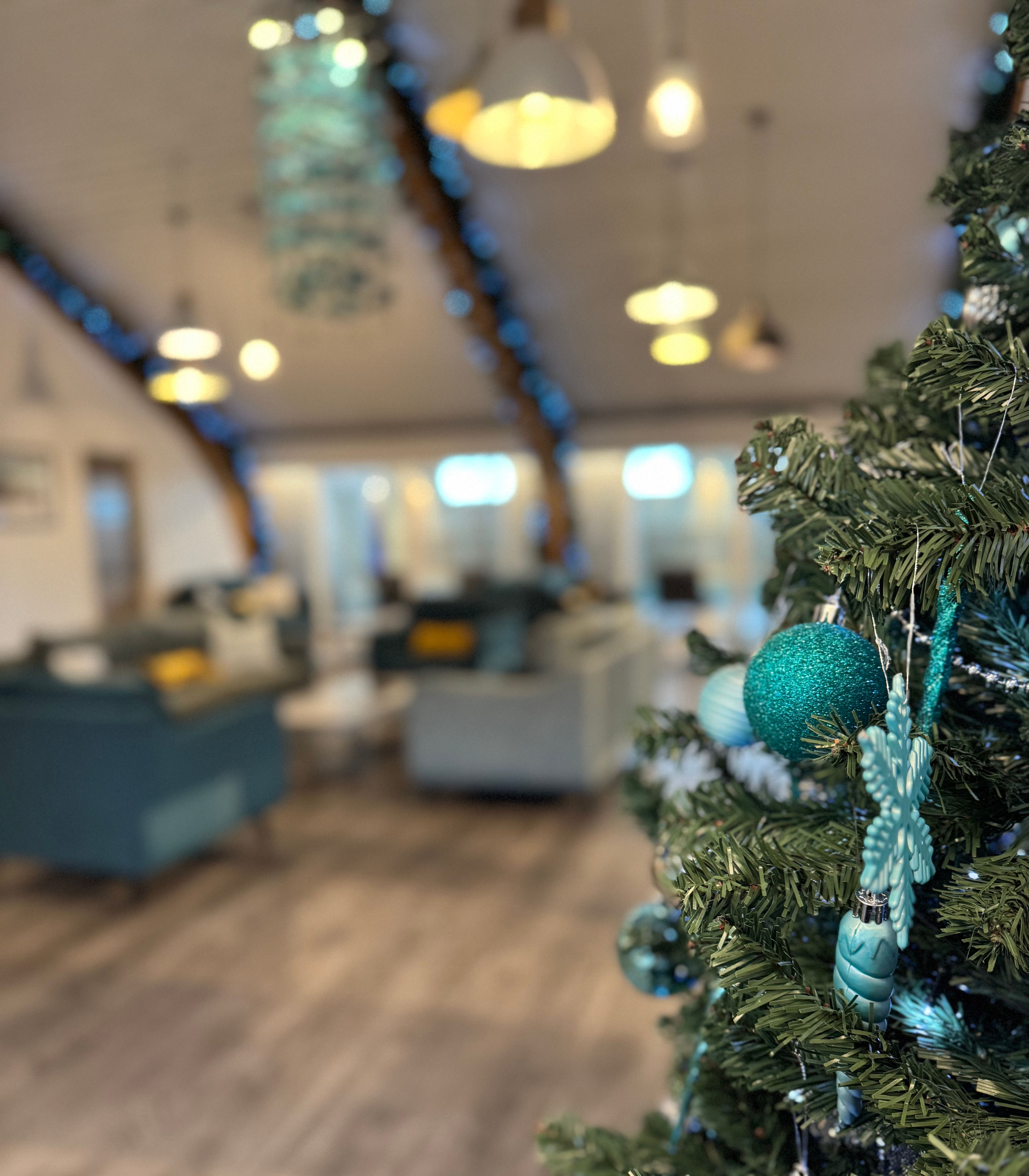 A decorated Christmas tree with teal ornaments in a modern, cozy living room.