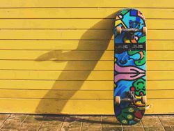 Colorful skateboard leaning against a yellow wooden wall