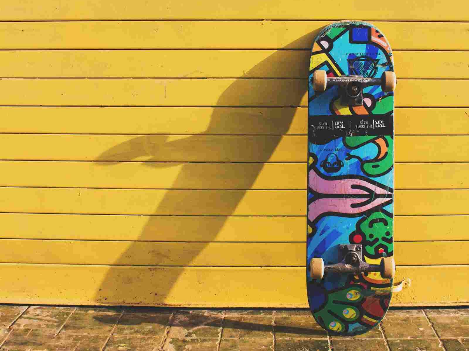 Colorful skateboard leaning against a yellow wooden wall