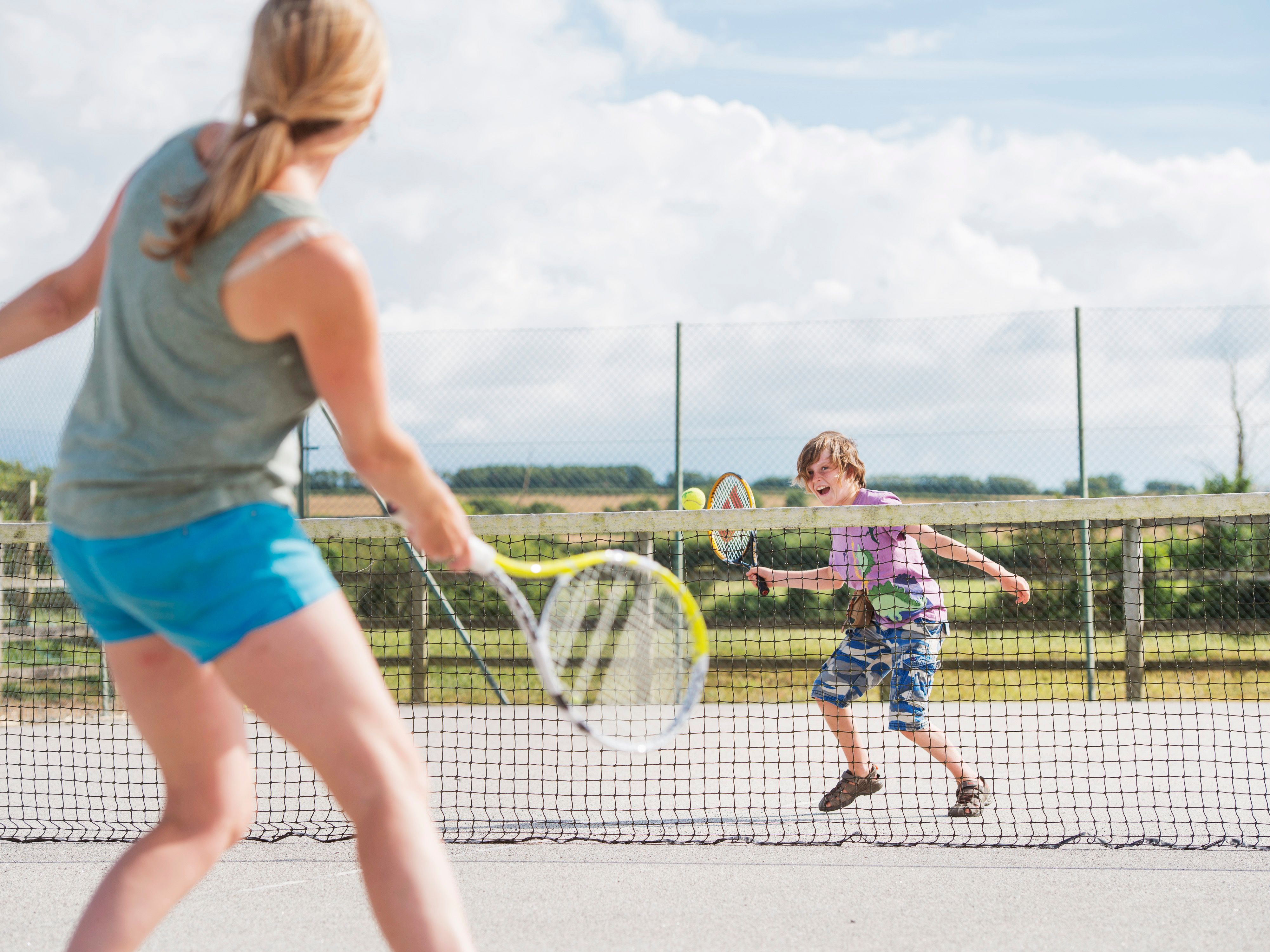Woman and child playing tennis on an outdoor court