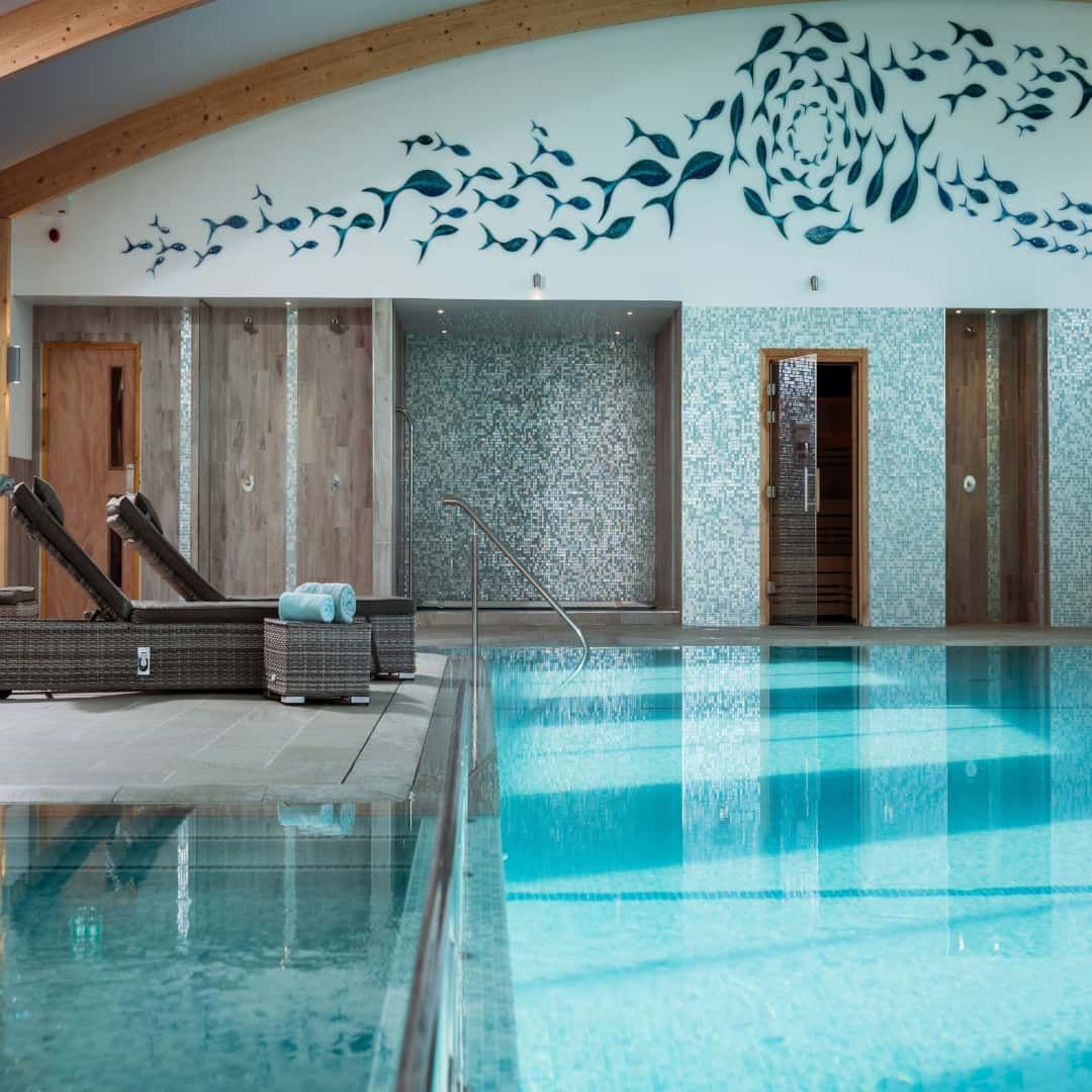 Indoor swimming pool area with lounge chairs and modern wall art