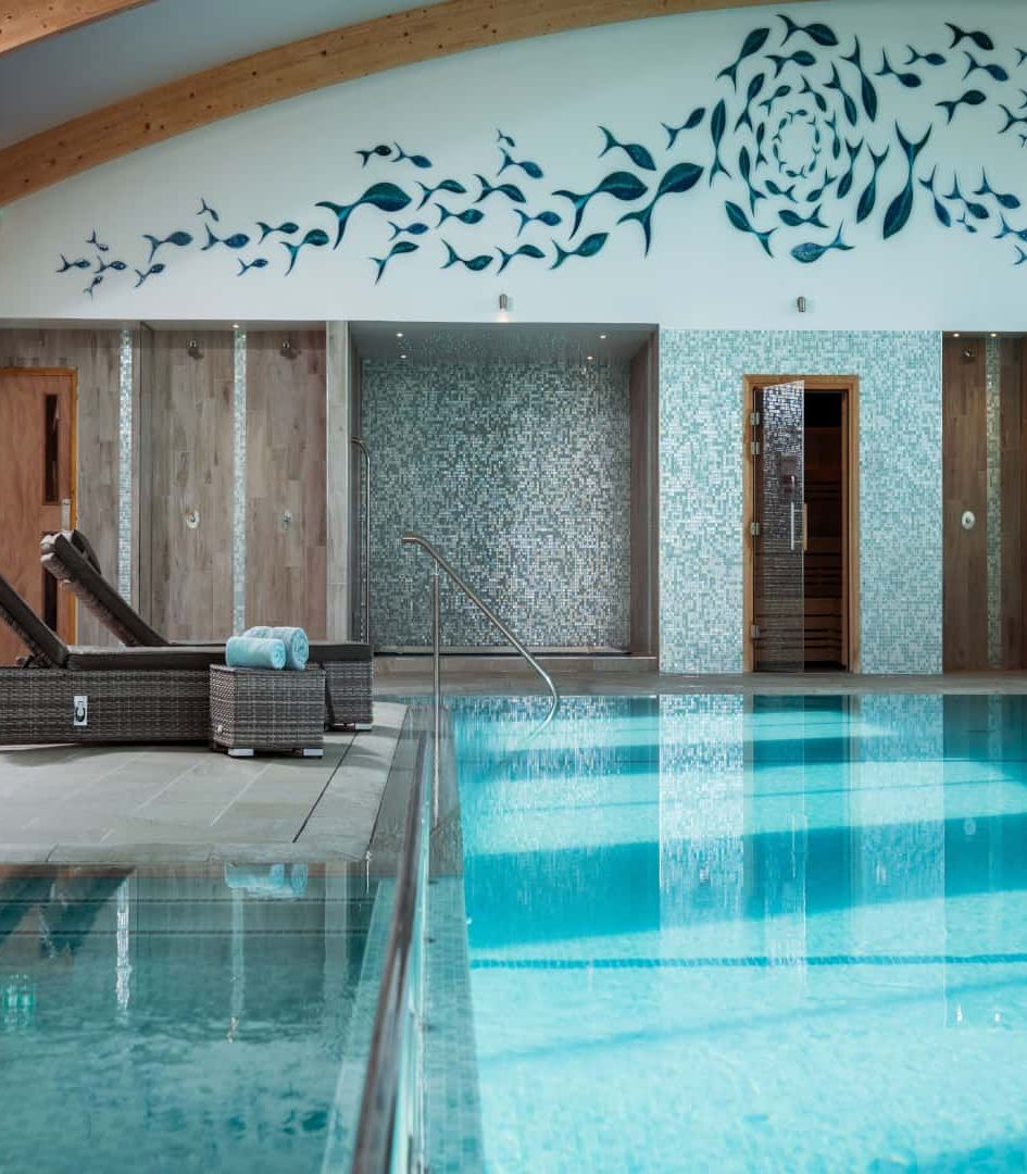 Indoor swimming pool area with lounge chairs and modern wall art