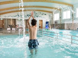 Boy playing in an indoor swimming pool with water splashing around