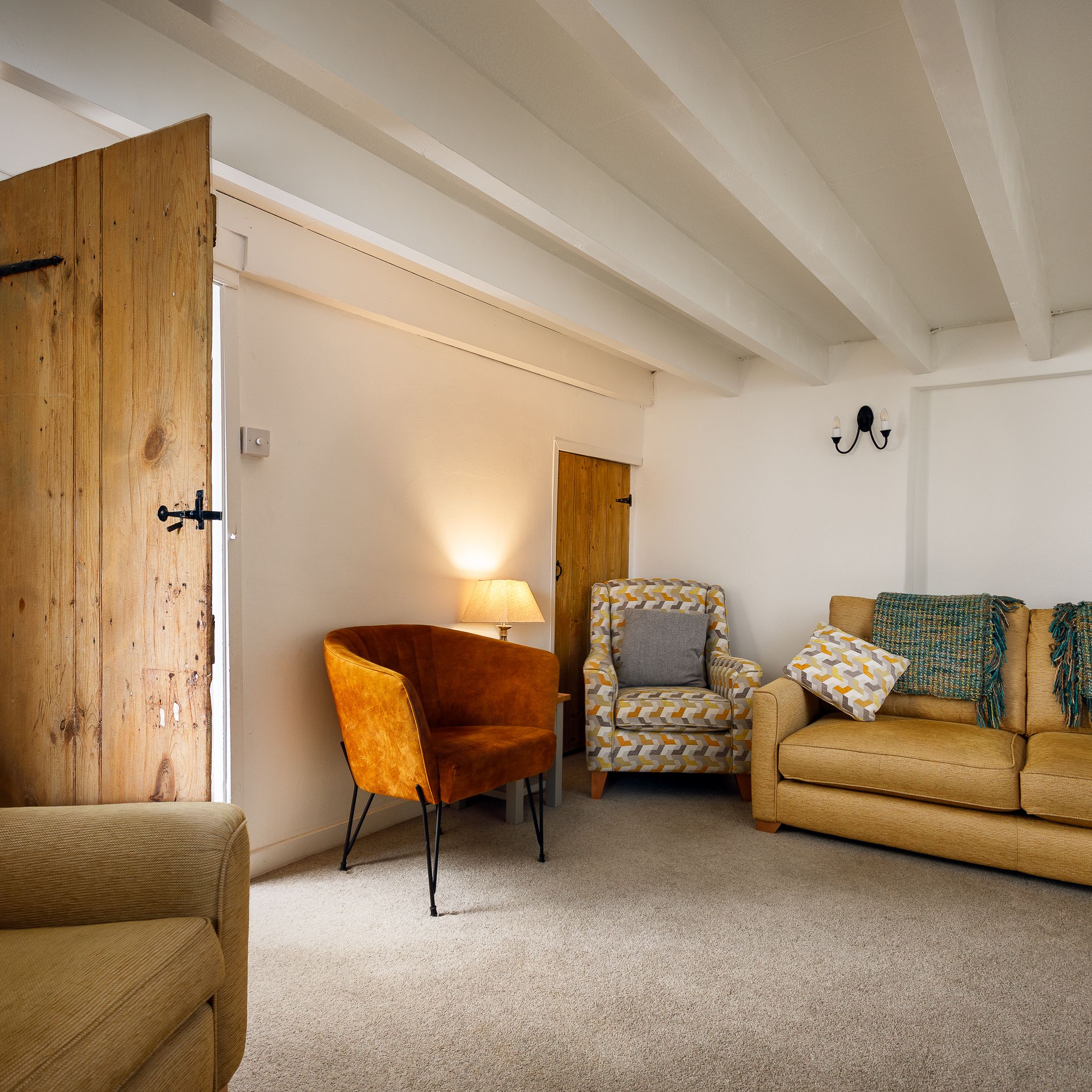 Cozy living room with yellow furniture, patterned cushions, and exposed wooden door