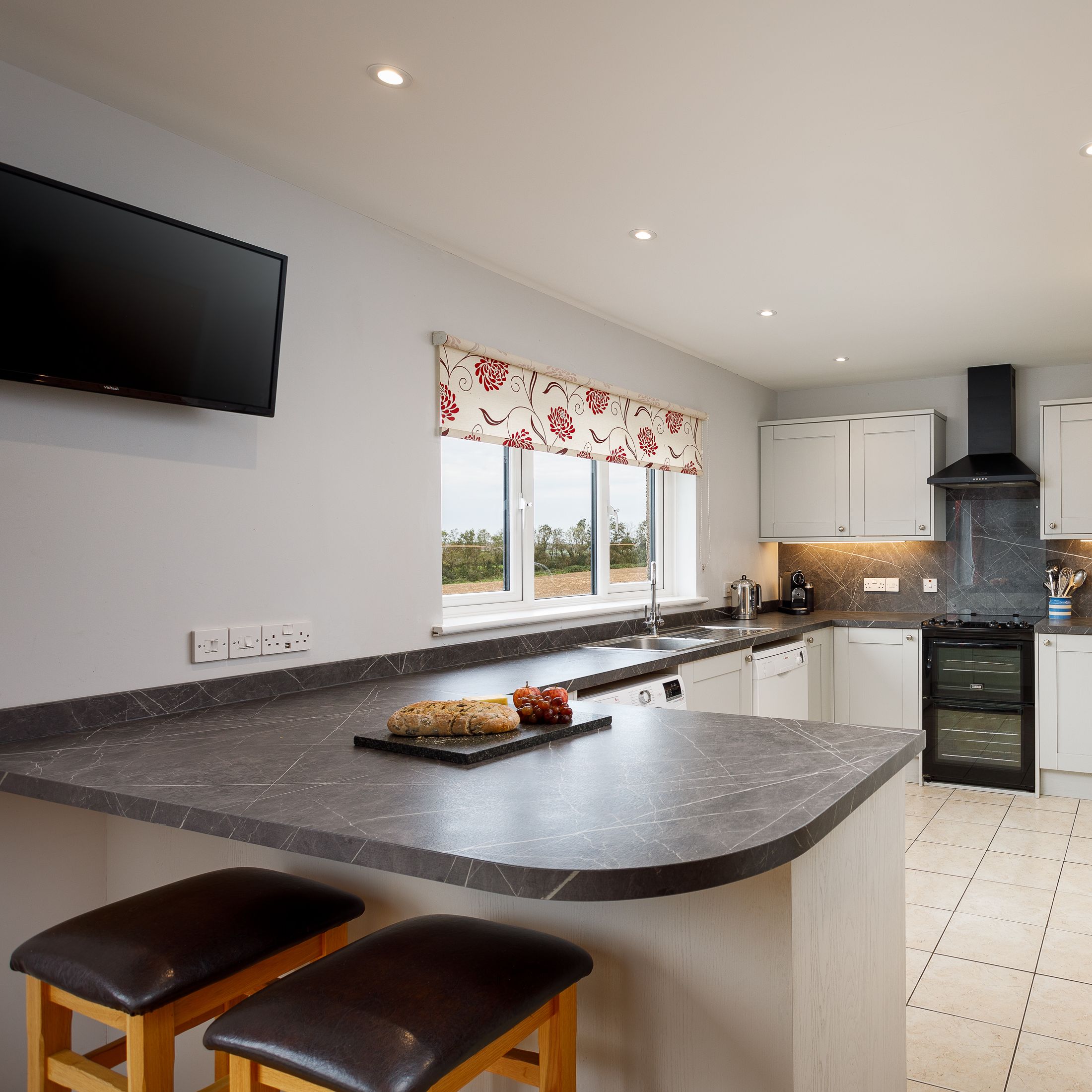 Modern kitchen with white cabinetry, black countertops, and breakfast bar seating.