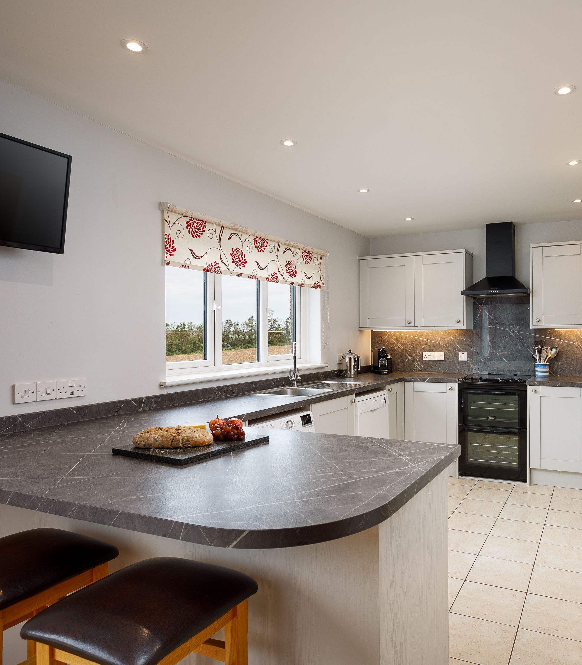 Modern kitchen with white cabinetry, black countertops, and breakfast bar seating.