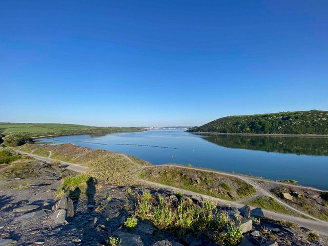 Scenic view of a calm lake surrounded by green hills under a clear blue sky